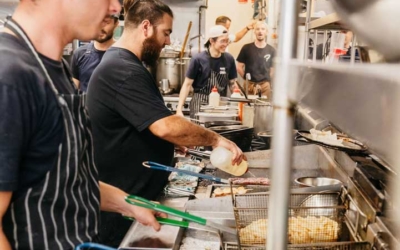 Settlers_Tavern_Food_OBJ886928 Cooks work together in a busy kitchen, using frying equipment and preparing food.