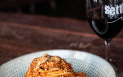 Settlers_Tavern_Food_OBJ887394 A plate of spaghetti with tomato sauce and a glass of red wine on a wooden table.