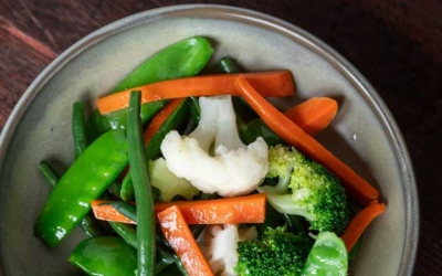 Settlers_Tavern_Food_OBJ887411 A bowl of fresh mixed vegetables, including snow peas, green beans, carrots, broccoli, and cauliflower, on a wooden table.